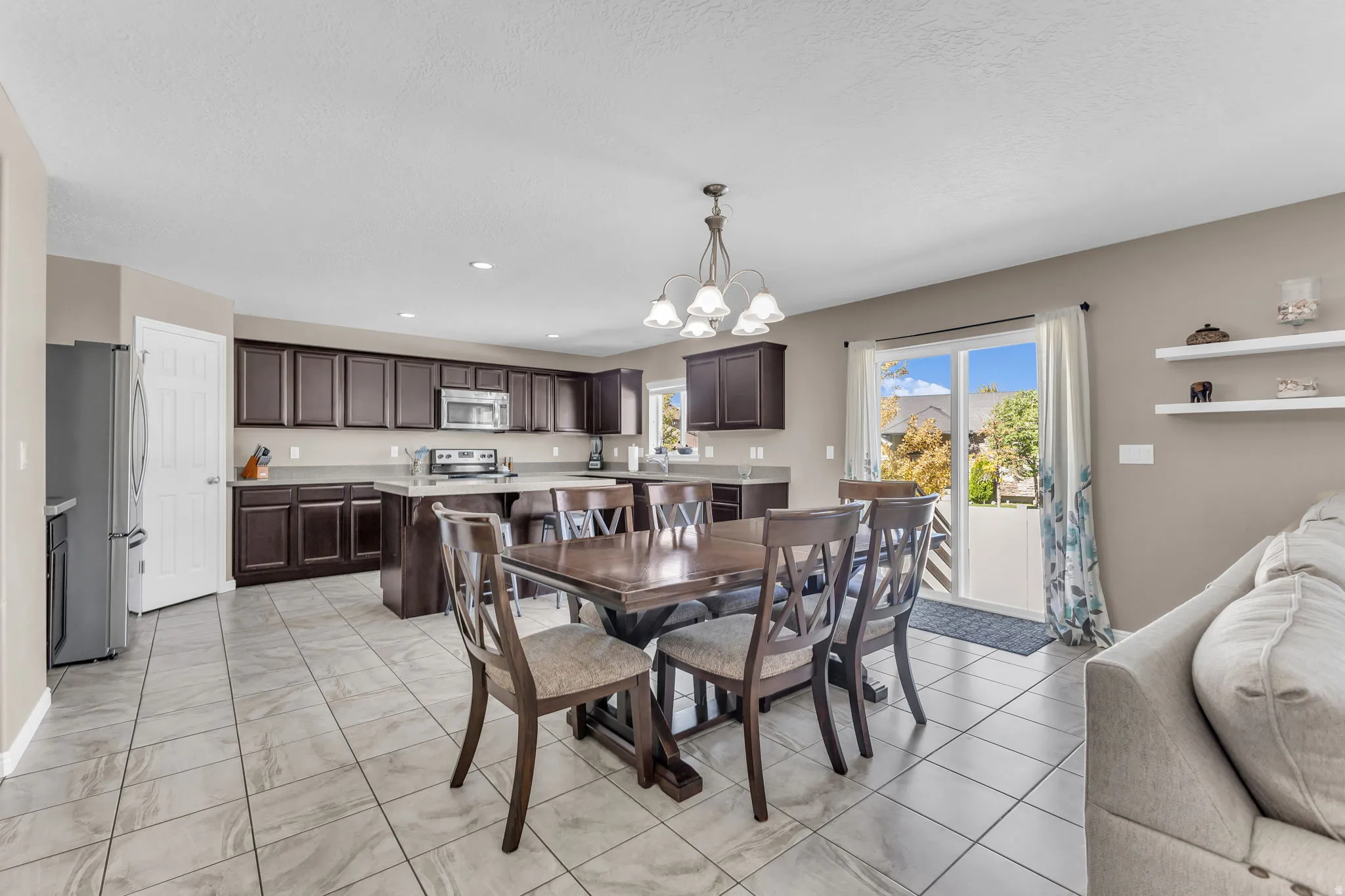 Kitchen featuring dark wood cabinetry, stainless steel appliances, and a central island with bar seating