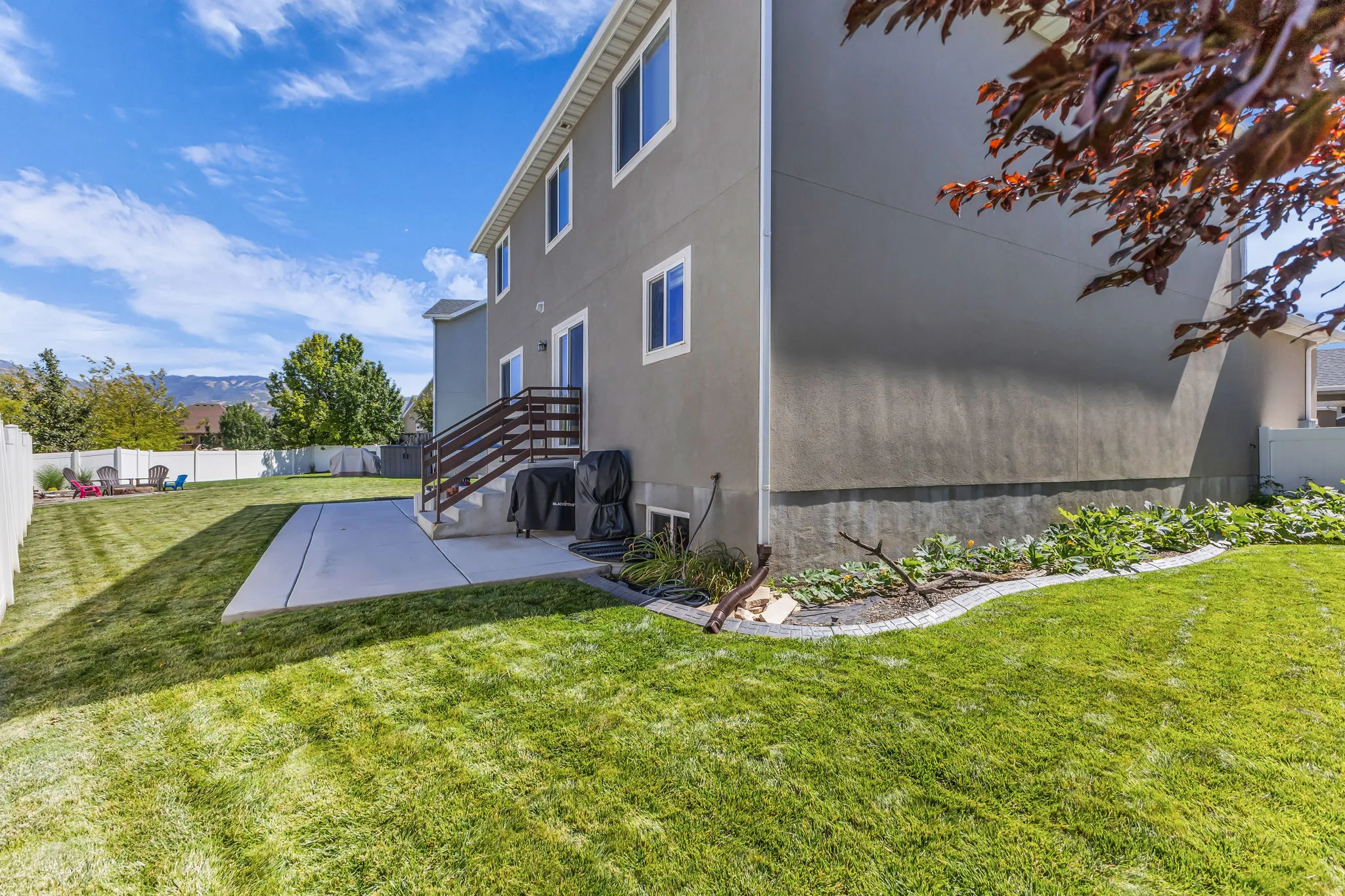 Expansive lawn area with a concrete patio and a raised landscaping bed