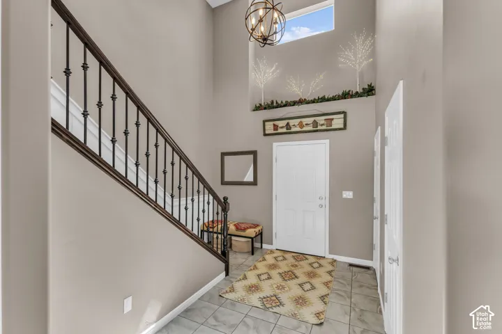 Two-story foyer with high ceilings, wrought iron staircase railing, overhead chandelier, and a transom window