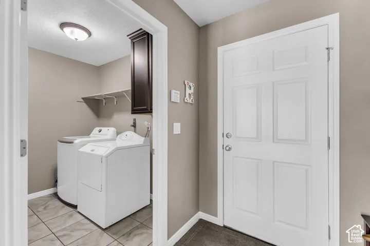 Utility area featuring tile flooring, wall-mounted shelving, and a built-in dark wood-finish cabinet