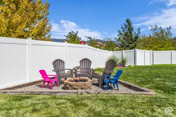 Private backyard with a white panel fence, stone fire pit, and landscaped gravel area