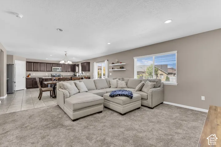 Spacious open-concept living area with plush carpeting, recessed lighting, and a large window