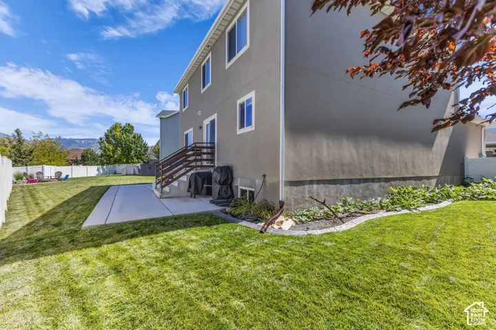 Expansive lawn area with a concrete patio and a raised landscaping bed