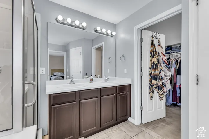 Double vanity with white countertop, brown cabinetry, and chrome fixtures