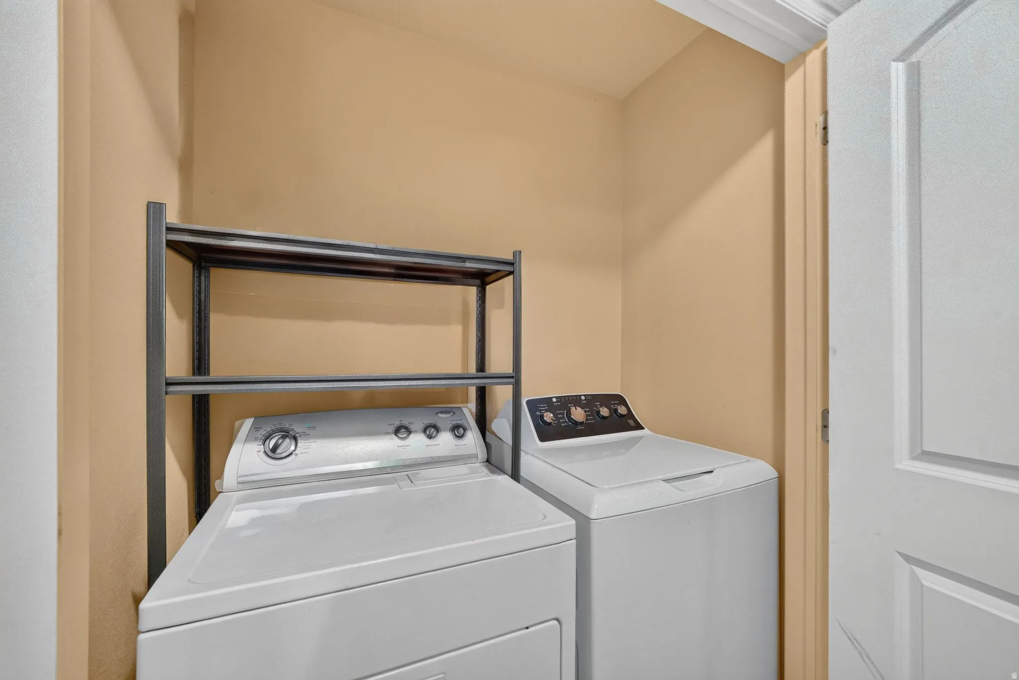 Dedicated laundry area featuring a washer and dryer, accompanied by a metal storage rack