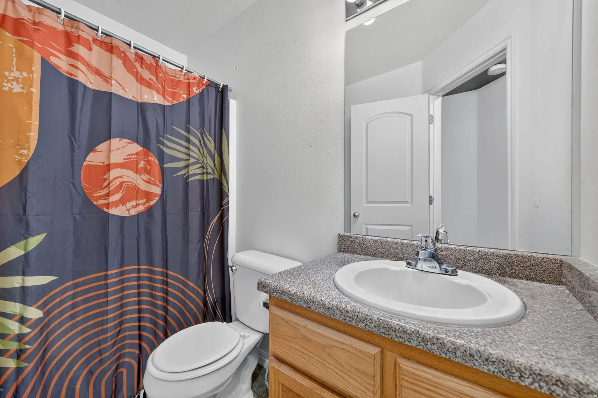 Bathroom featuring a single vanity with an oval basin, chrome faucet, and integrated backsplash