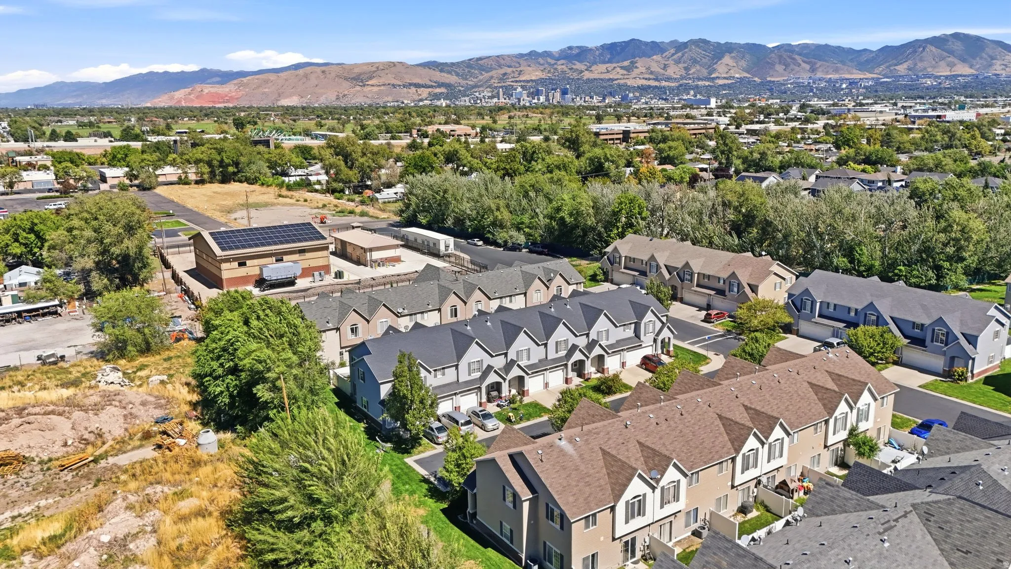 Aerial perspective showcasing multiple townhouse-style properties, varied rooflines, and mature perimeter trees