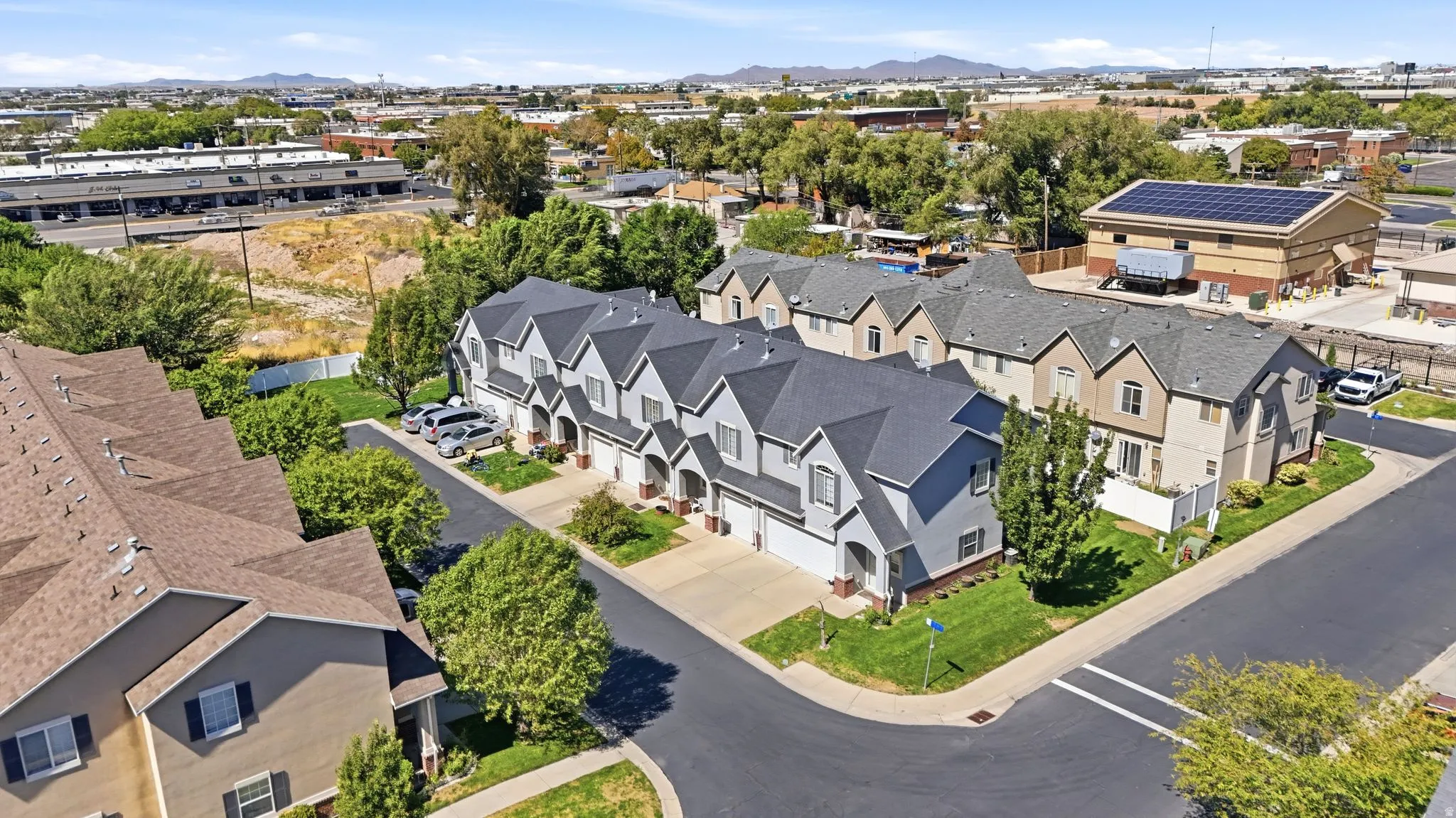 Townhome community with multiple units, paved roadways, and green landscaping