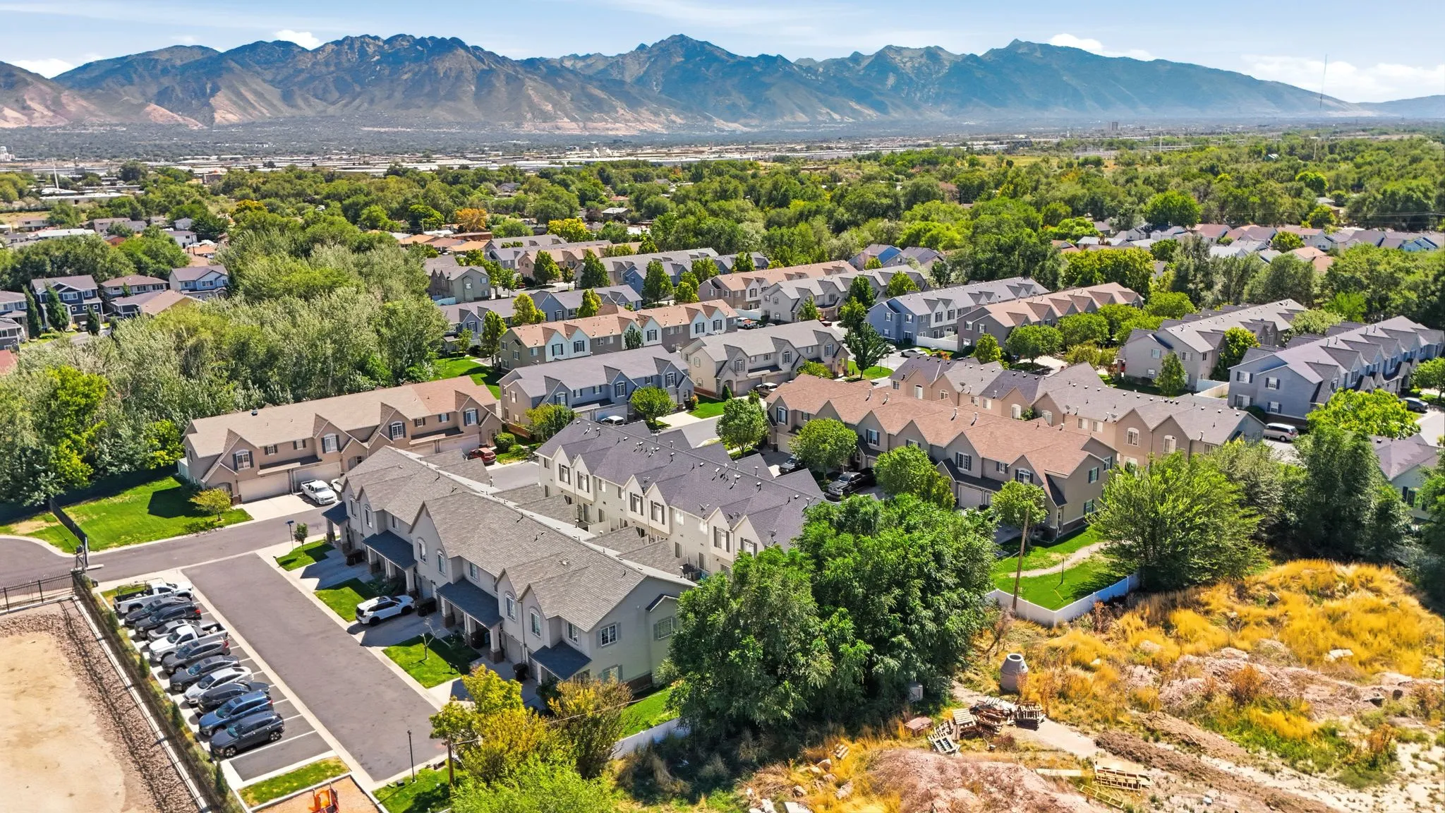 Residential community featuring a variety of housing styles, abundant mature trees, and mountainous terrain in the background