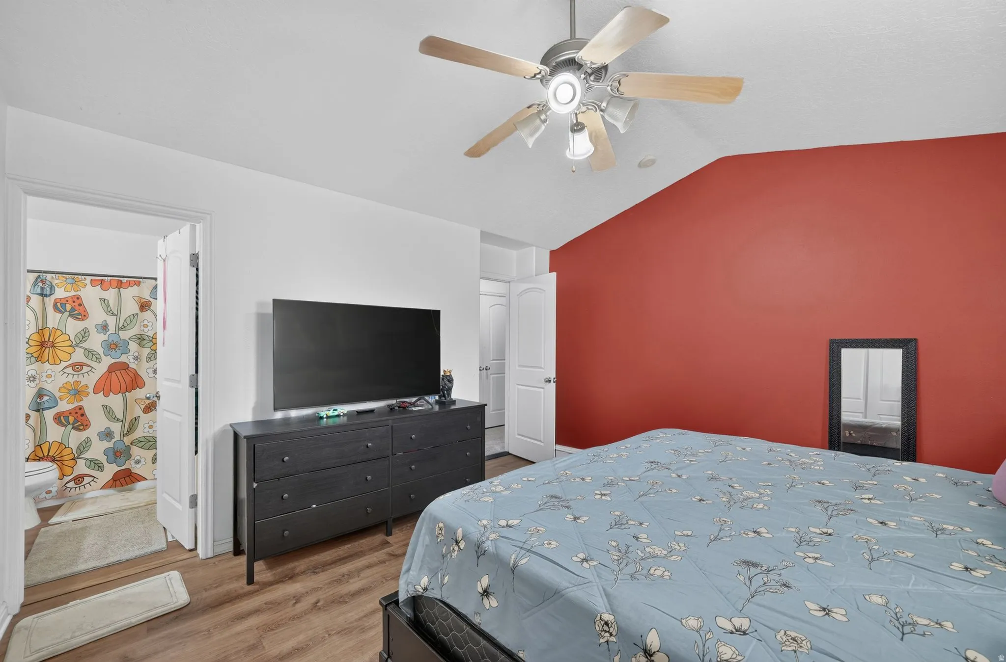 Sloped ceiling with ceiling fan, wood-finish flooring, and a built-in dresser