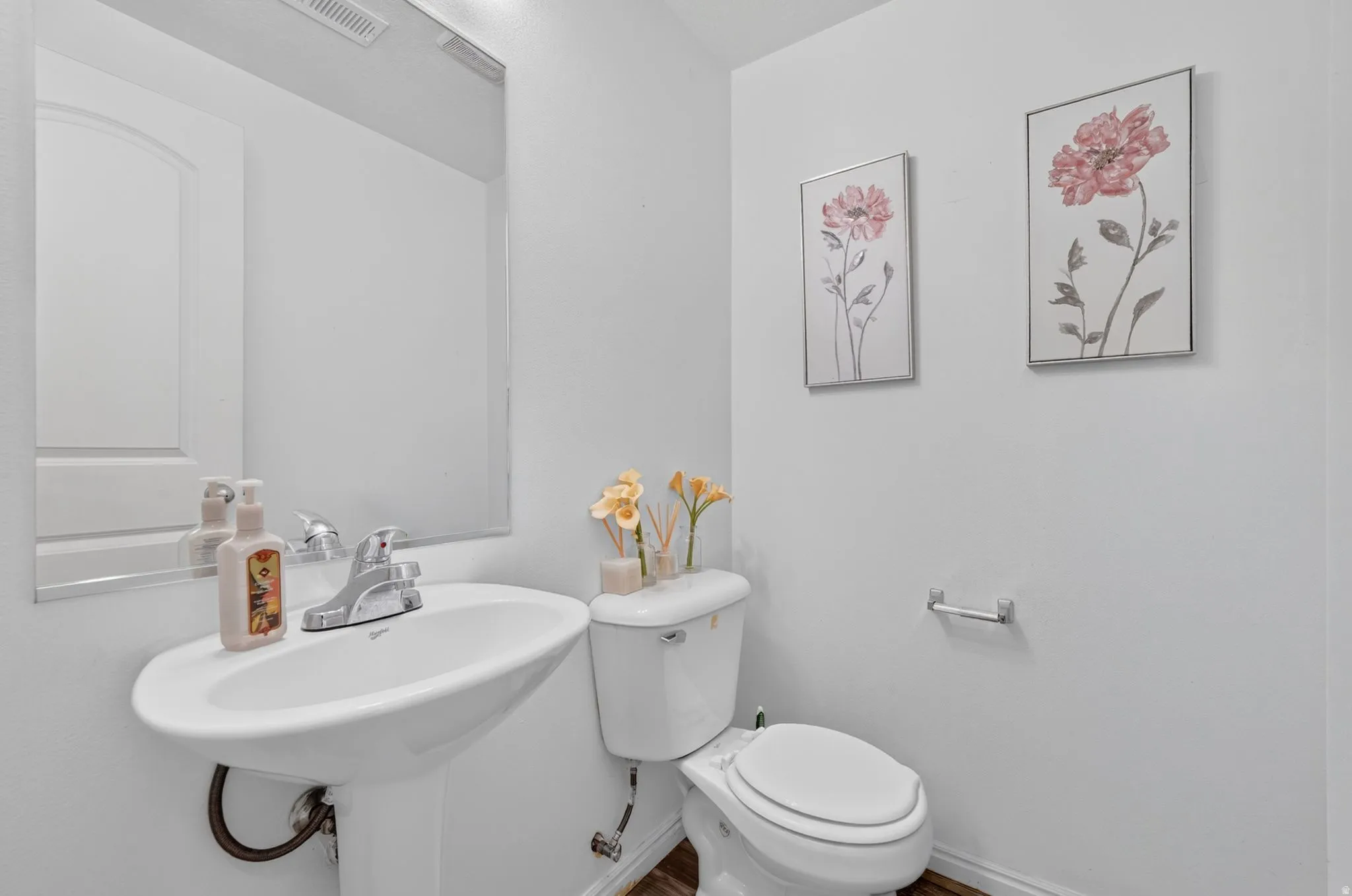 Pedestal sink with chrome faucet, toilet, and rectangular wall mirror