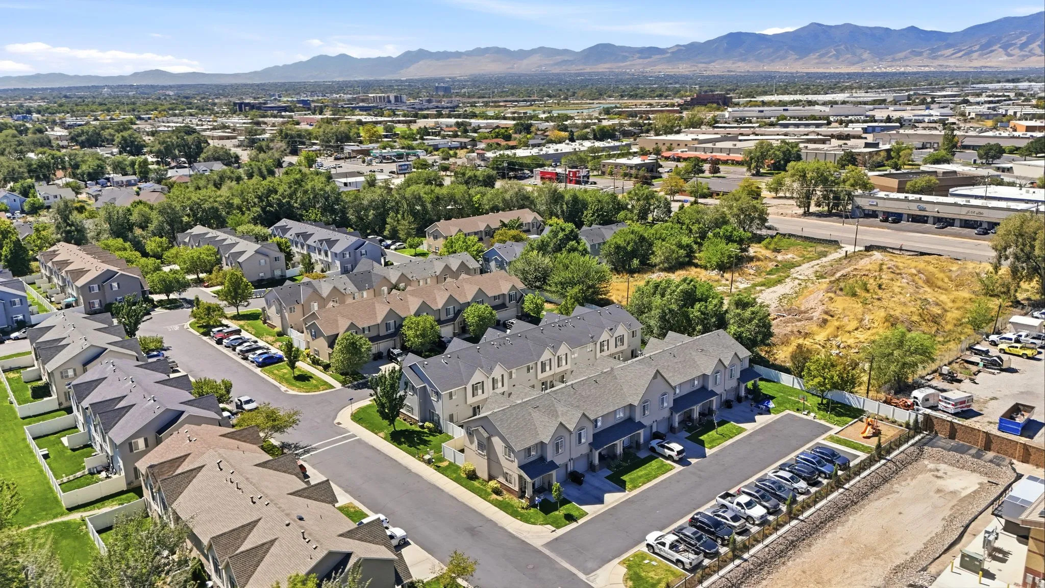 Townhome community featuring multi-story residences, paved roadways, and landscaped green spaces