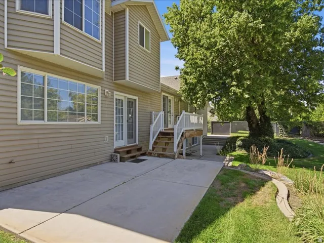 Concrete patio with a mature shade tree, extending to a manicured lawn