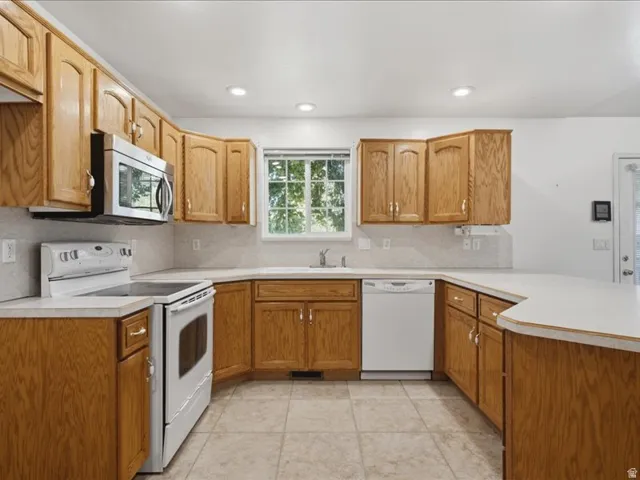 Full kitchen featuring wood cabinetry, white countertops, tile flooring, and recessed lighting