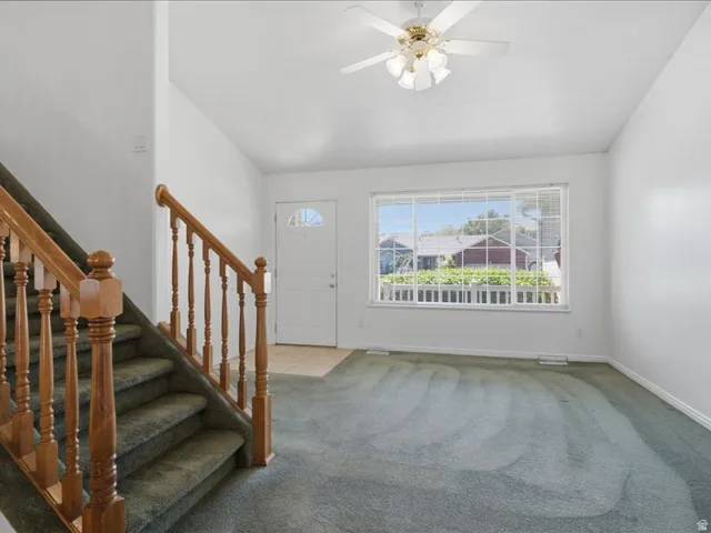 Entryway featuring a wood staircase with balusters, a white front door with an arched window, and tiled flooring