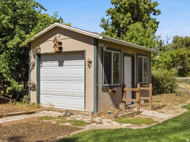 Detached structure featuring a paneled garage door, two windows, and a side entry door
