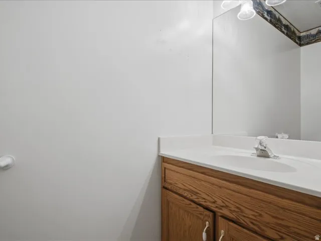 Wood-finish vanity with cabinet storage, integrated sink, and white countertop