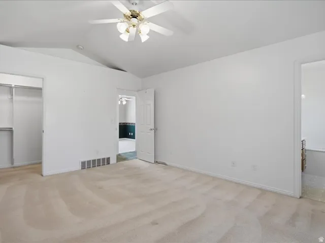 Neutral carpet flooring with an overhead ceiling fan and light fixture