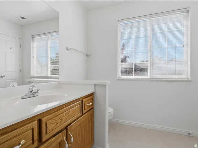 Bathroom vanity with wood-finish cabinetry, integrated sink, and chrome faucet