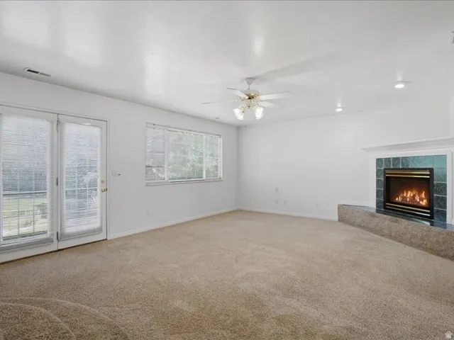 Recessed lighting, ceiling fan, carpet flooring, fireplace with tile surround, and French doors