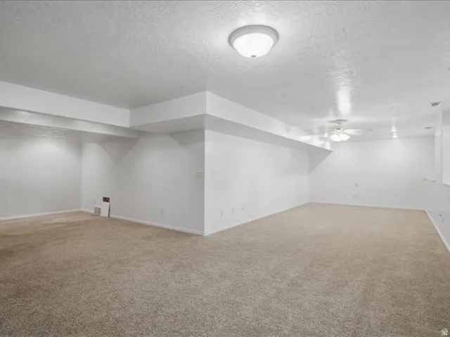 Spacious room featuring neutral carpeting, white painted walls, and overhead lighting