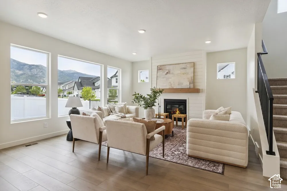 Living area featuring wood-finish flooring, a contemporary fireplace with a wood mantel, recessed lighting, and multiple large windows