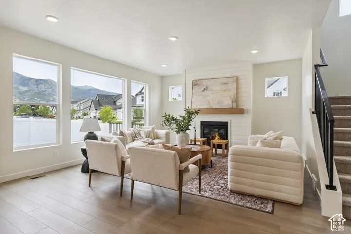 Living area featuring wood-finish flooring, a contemporary fireplace with a wood mantel, recessed lighting, and multiple large windows
