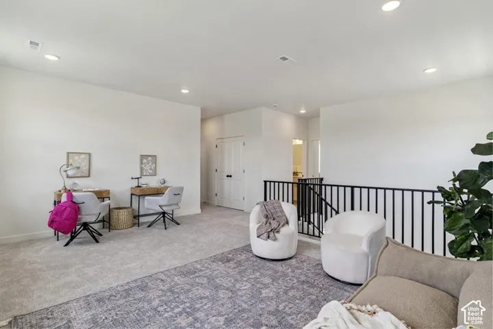 Carpeted open-concept bonus room featuring recessed lighting and a black metal railing