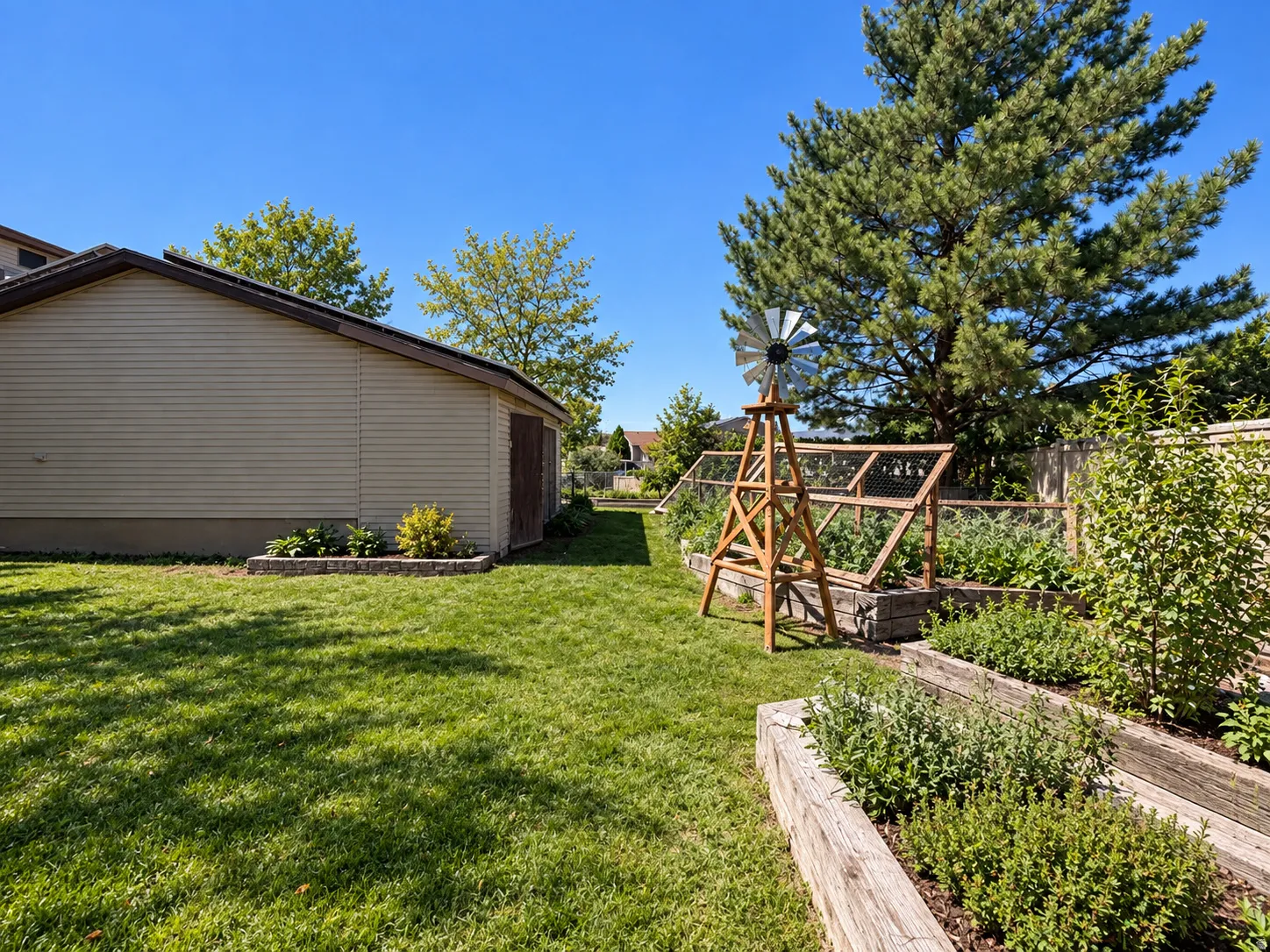 Expansive manicured lawn with raised garden beds, wood-finish storage shed, and mature perimeter trees