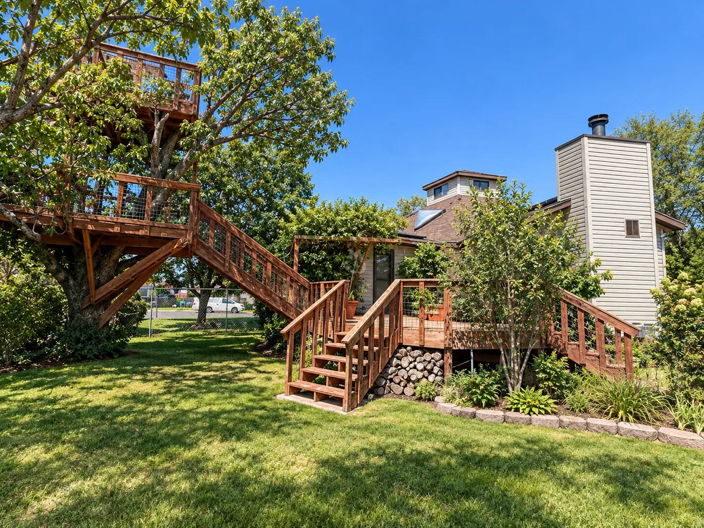Expansive lawn with a custom treehouse structure, wood decking, and a wood-sided exterior