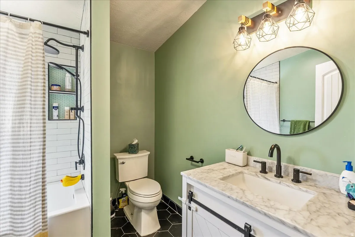 Bathroom featuring a white vanity with a stone countertop, an undermount sink, and black fixtures