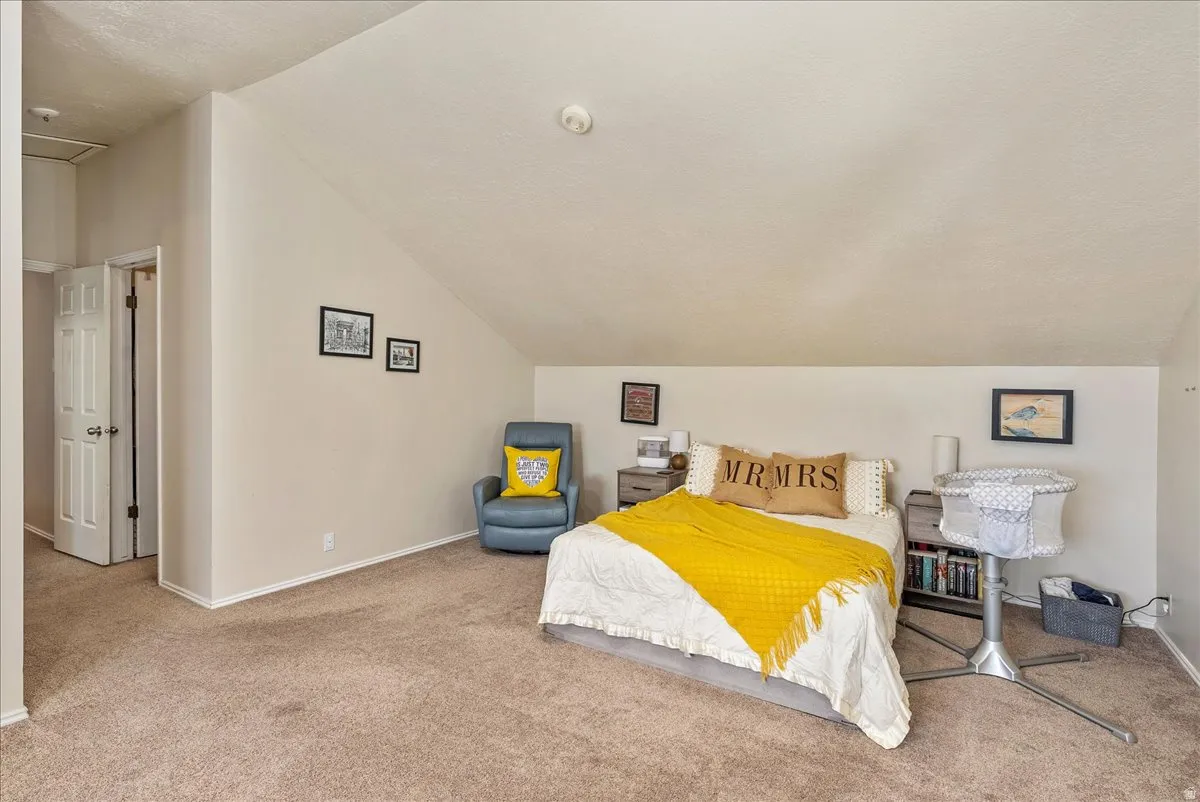 Carpeted room featuring a sloped ceiling and neutral wall tones