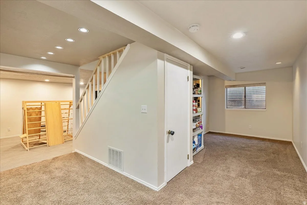 Carpeted flooring, recessed lighting, white painted walls, built-in shelving, and a window with blinds