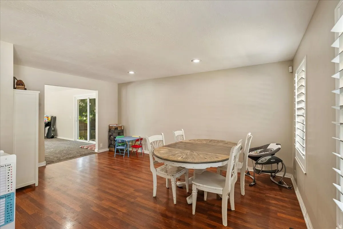Wood-finish flooring, recessed lighting, plantation shutters, and sliding glass door