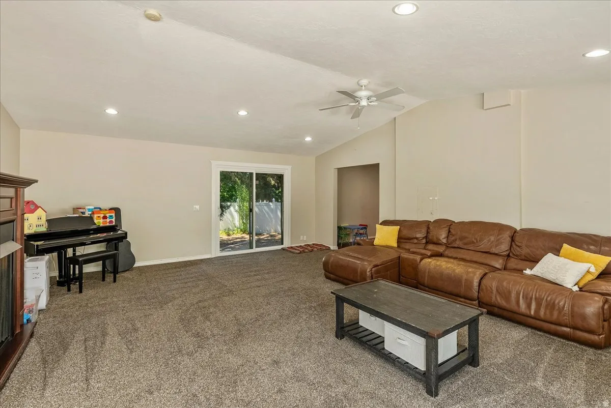 Vaulted ceiling, recessed lighting, ceiling fan, and sliding glass door