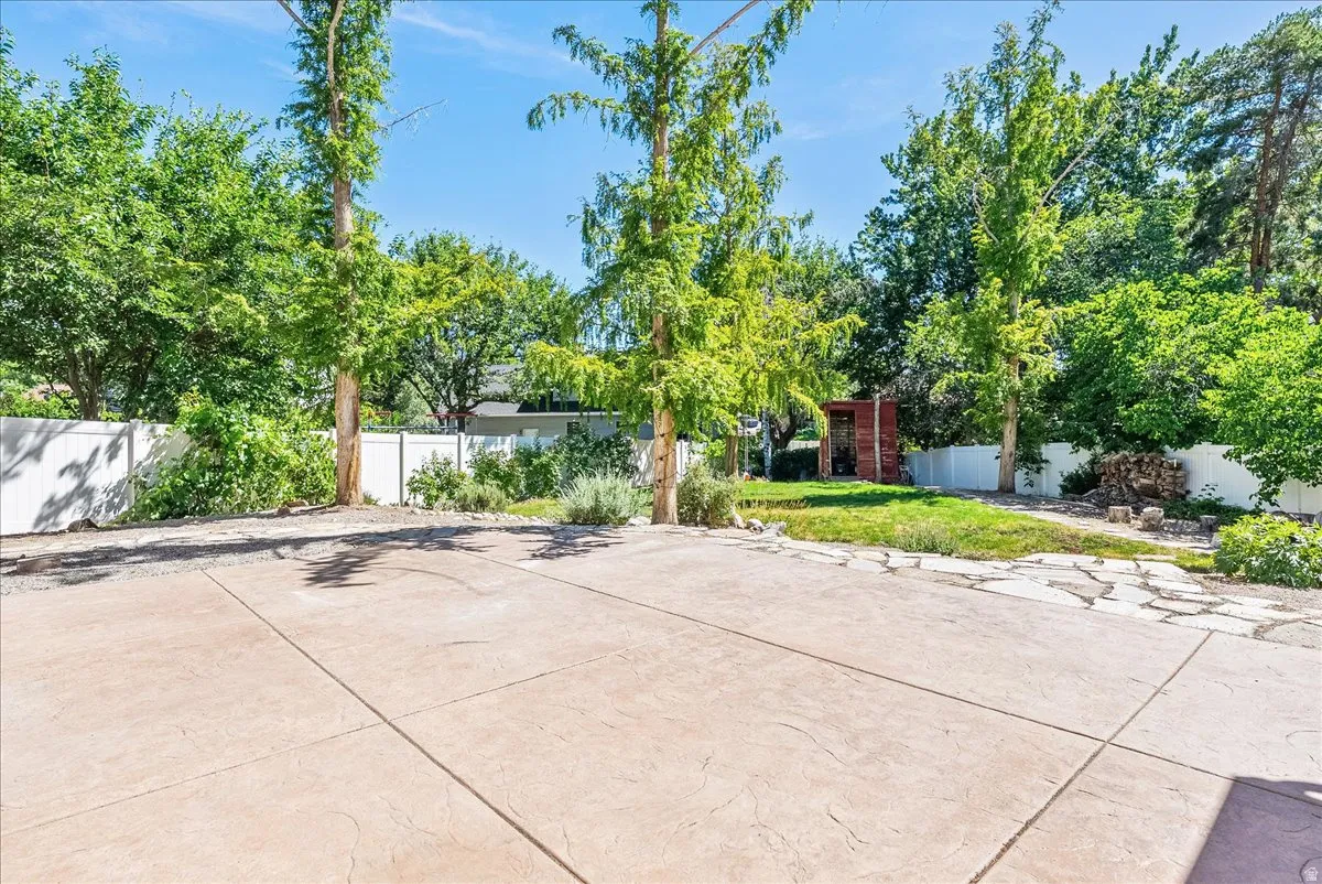 Stamped concrete patio with perimeter landscaping and established trees