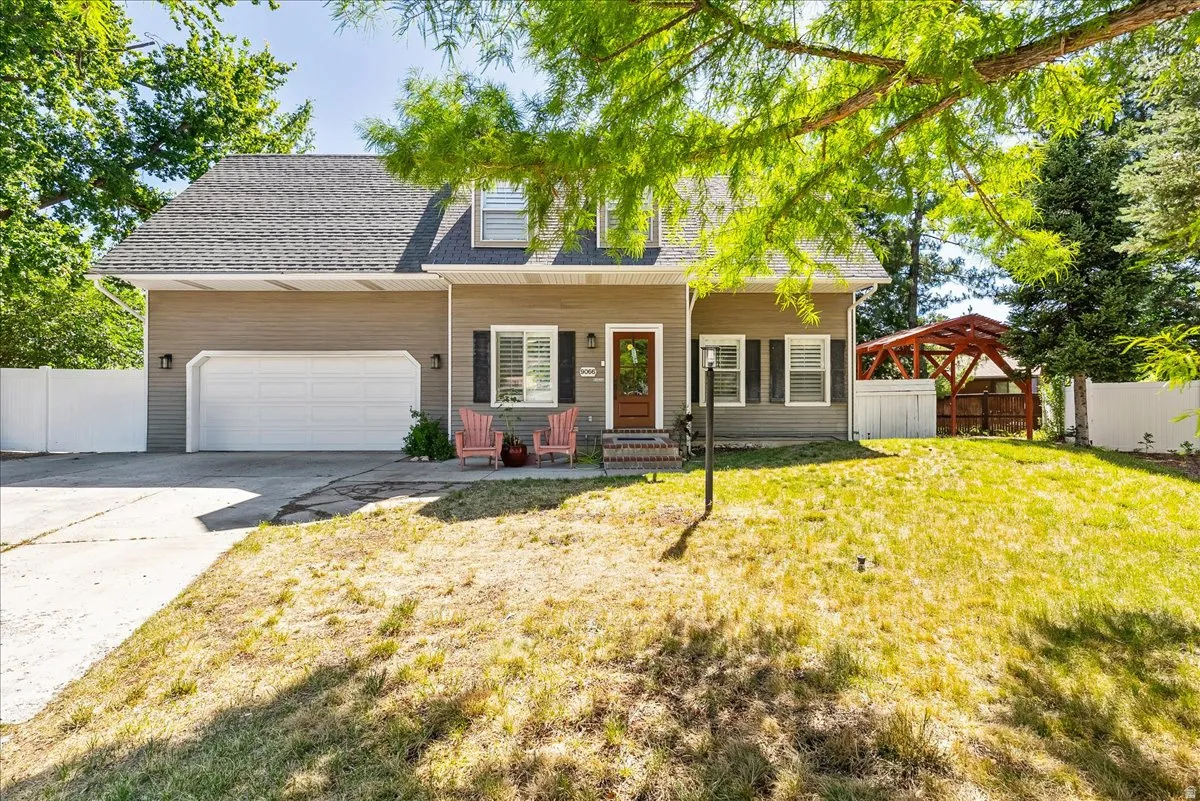 Siding exterior with a two-car garage, white privacy fencing, and a separate covered structure