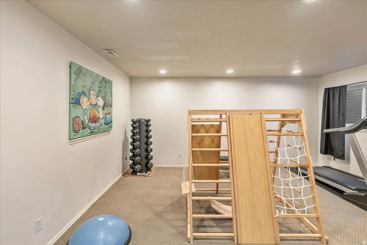 Recessed lighting illuminates the carpeted flooring and light-toned walls