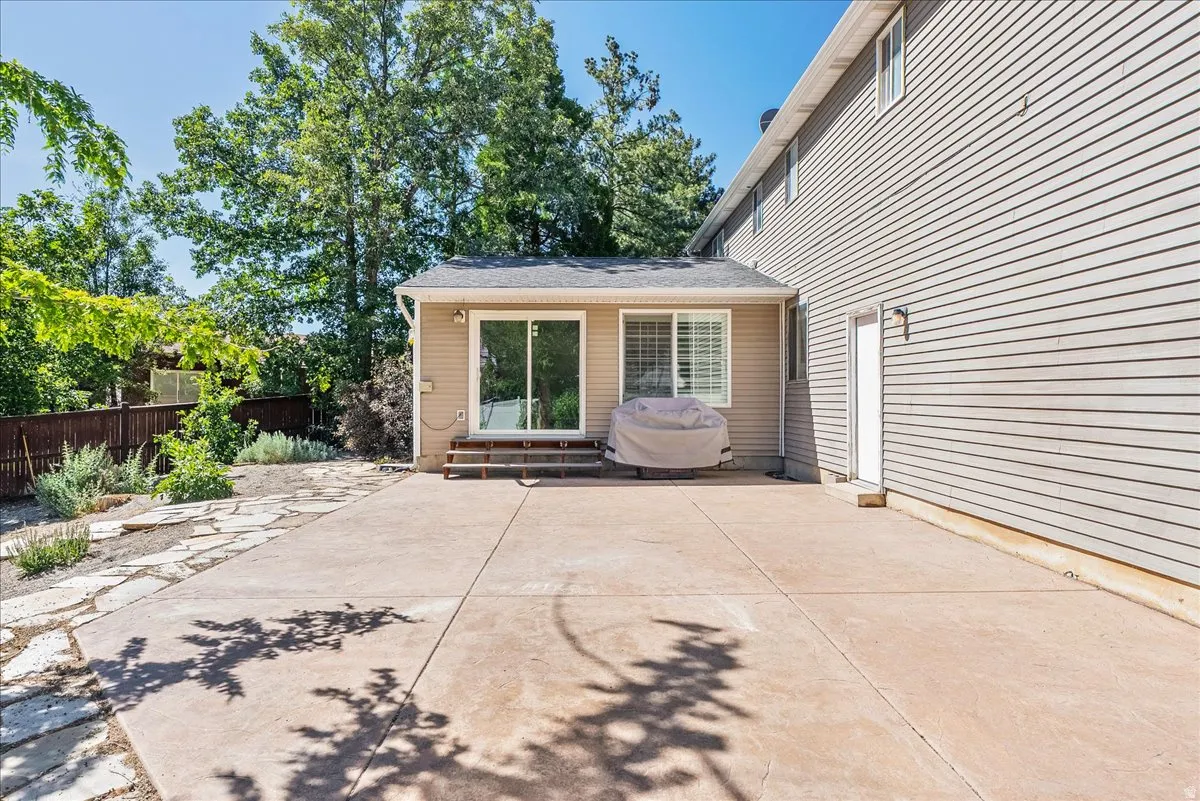 Expansive concrete patio with a flagstone path, sliding glass door access, and a secondary entry door