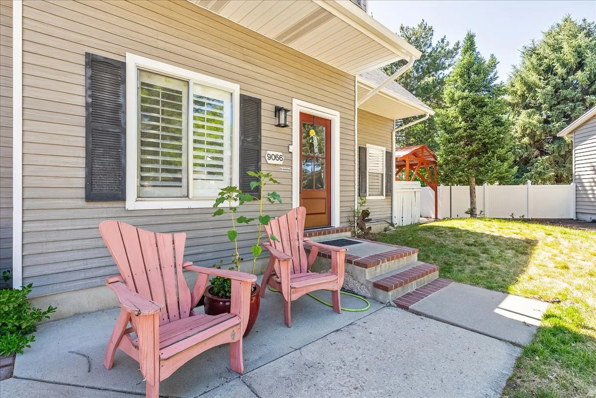 Siding exterior with contrasting shutters, concrete walkway, brick risers, and a privacy fence