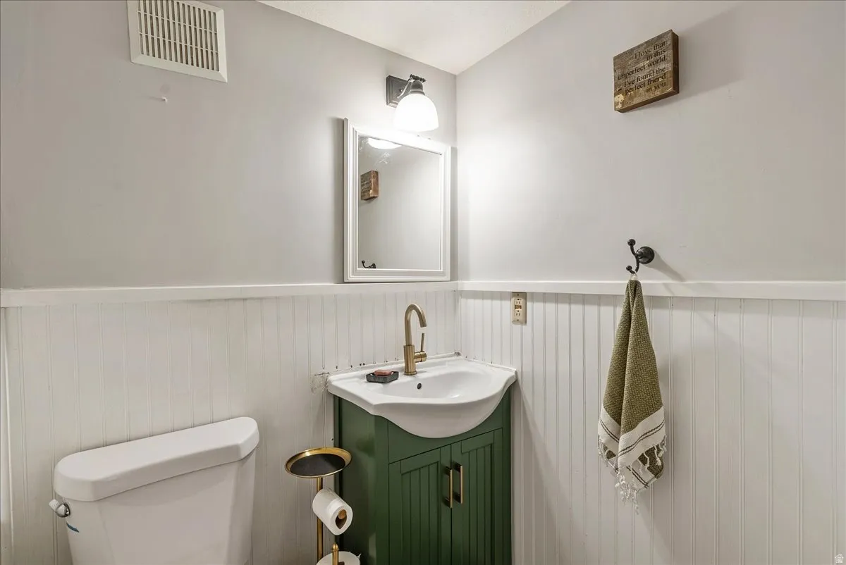 White beadboard wainscoting, wall-mounted mirror, and vanity with integrated sink and brass-finish faucet