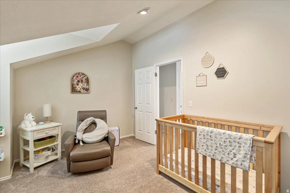 Carpeted flooring, vaulted ceiling, recessed lighting, and a white interior door