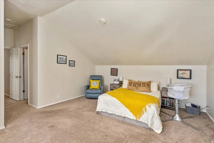 Carpeted room featuring a sloped ceiling and neutral wall tones
