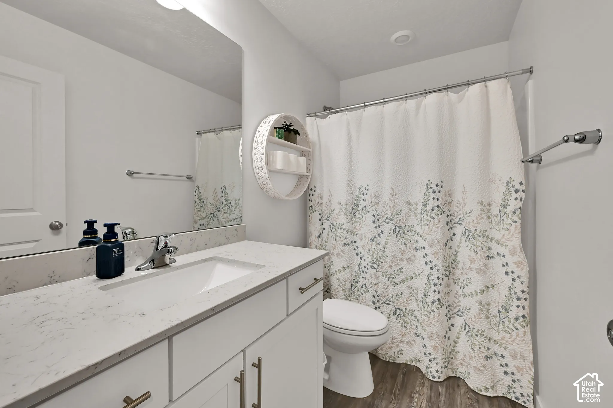 Bathroom featuring a single vanity with an integrated sink, light-toned countertop, and wood-finish flooring