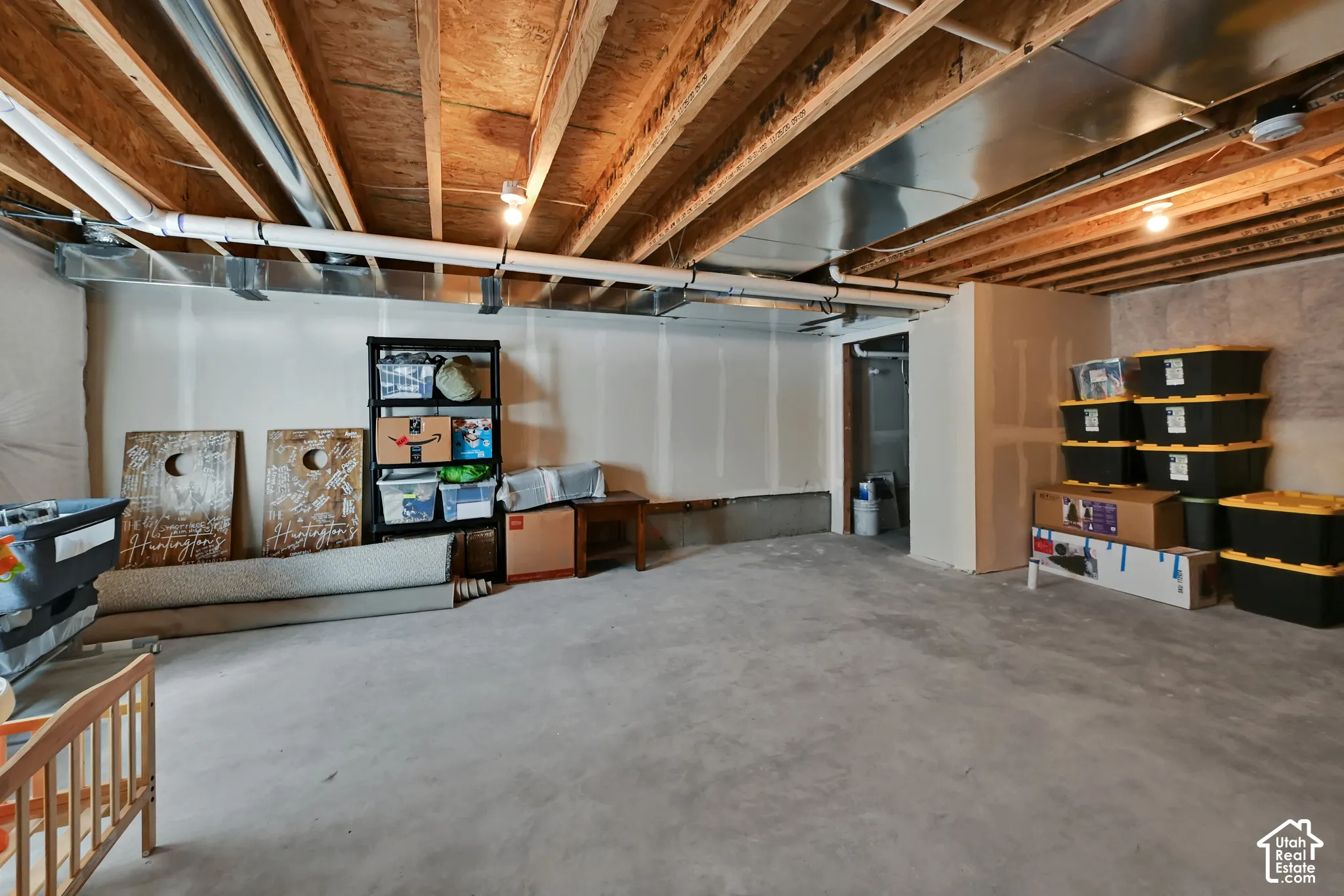 Unfinished lower level featuring exposed ceiling joists, concrete flooring, and partial drywall installation