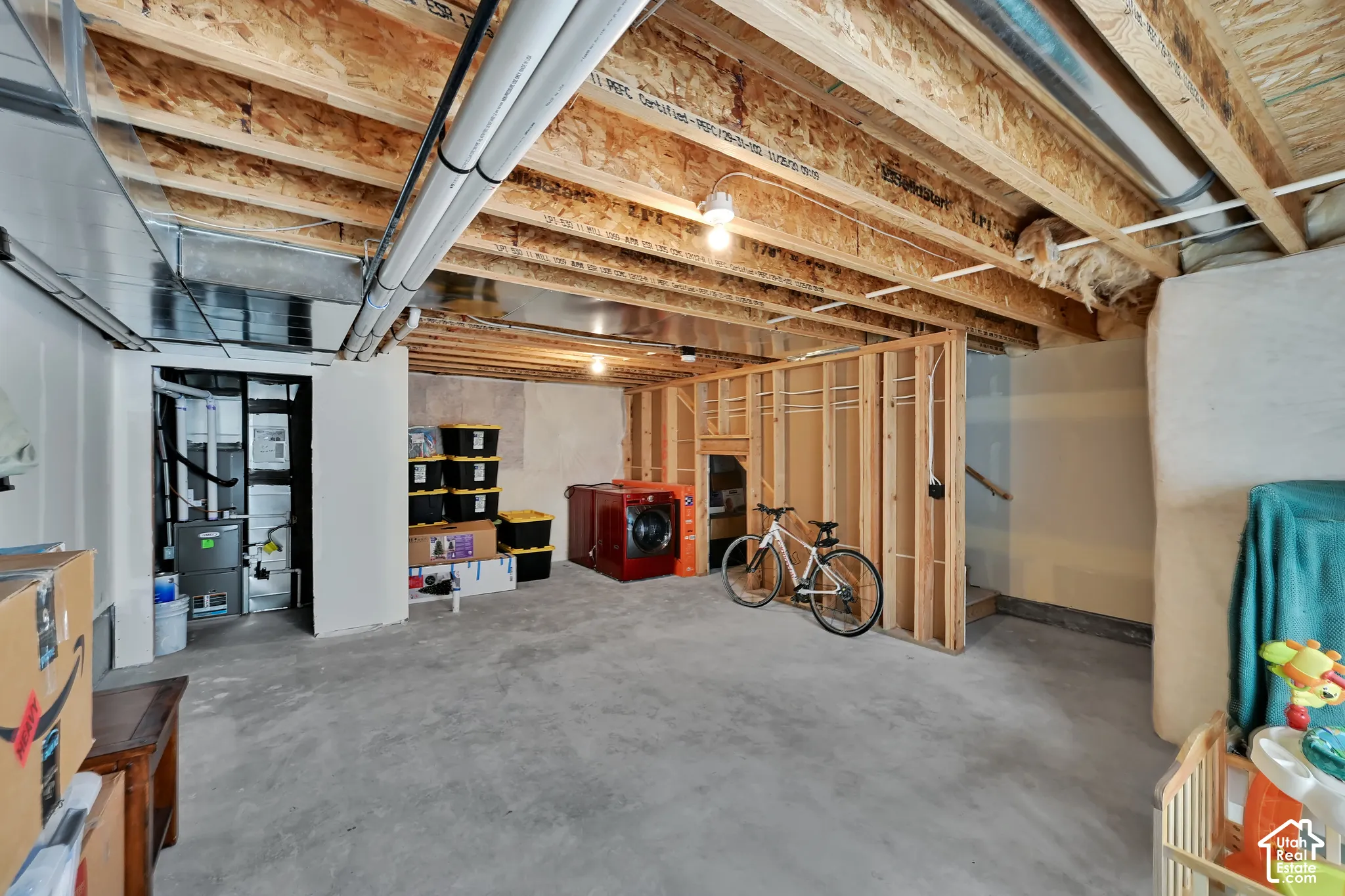 Unfinished basement featuring exposed wood joists, concrete flooring, and partial framing