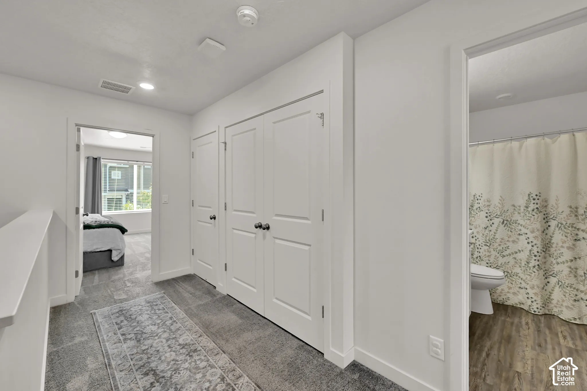 Carpeted hallway with white interior doors, built-in storage closets, and recessed lighting
