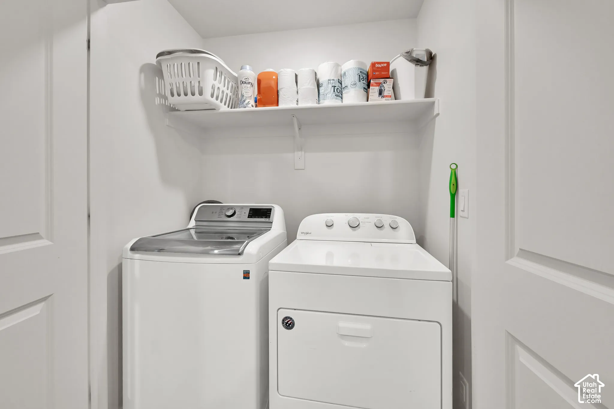 Dedicated laundry area featuring a built-in shelf for storage and a white paneled door