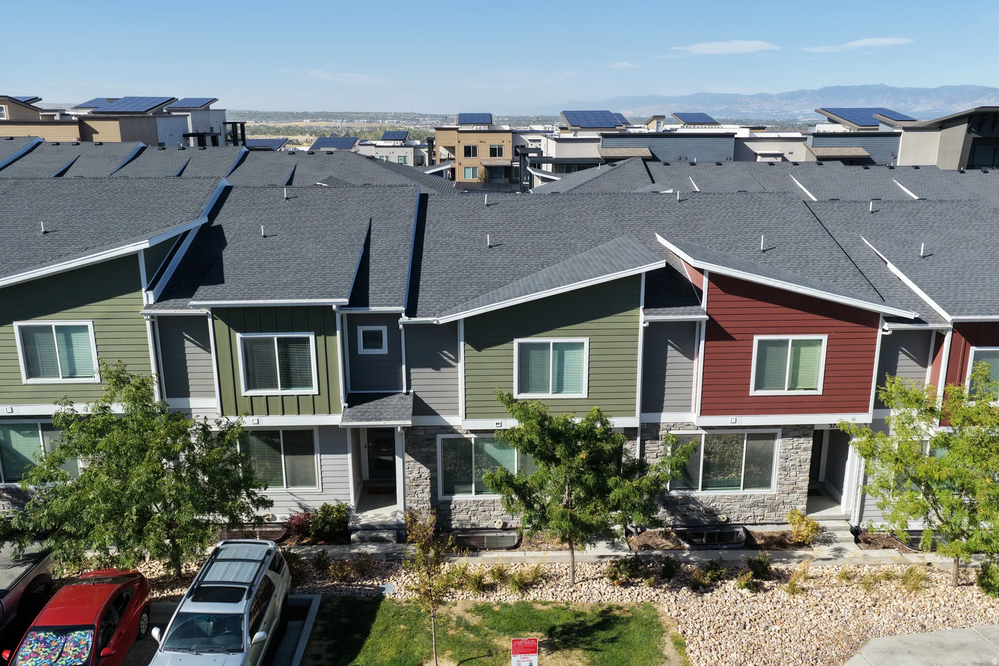 Townhome exterior featuring varied siding colors, stone accents, multiple windows, and a paved entrance
