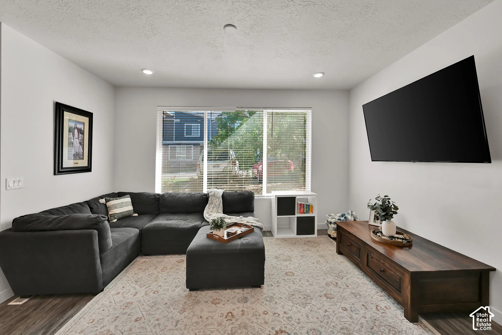 Recessed lighting, wood-finish flooring, and a large window with blinds